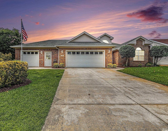 2479 Glen Dr, Little River, SC 29566 - view of front of home with a garage, concrete driveway, a lawn, and brick siding