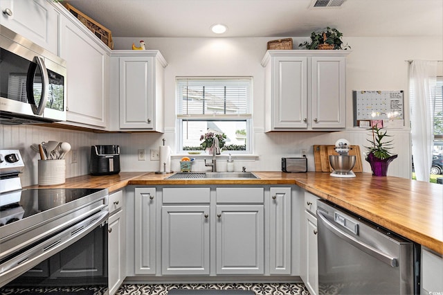 1209 Eagle Creek Dr, Myrtle Beach, SC 29588 - kitchen with stainless steel appliances, butcher block counters, a sink, and white cabinets