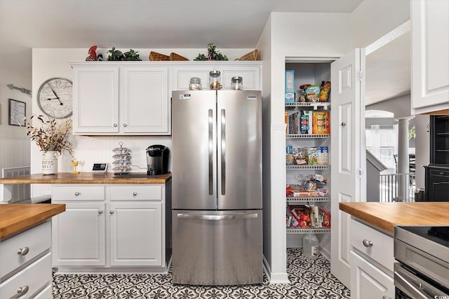 1209 Eagle Creek Dr, Myrtle Beach, SC 29588 - kitchen with butcher block countertops, freestanding refrigerator, white cabinetry, and light tile patterned floors