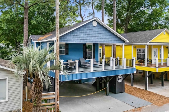 6001-1737 S Kings Hwy, Myrtle Beach, SC 29575 - rear view of property featuring a carport, roof with shingles, concrete driveway, and covered porch