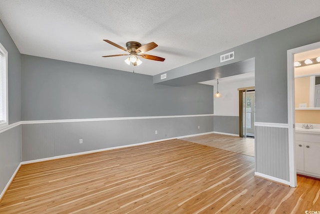 633 Sparrow Dr Unit B, Surfside Beach, SC 29575 - unfurnished room with light wood finished floors, a ceiling fan, a sink, baseboards, and wainscoting