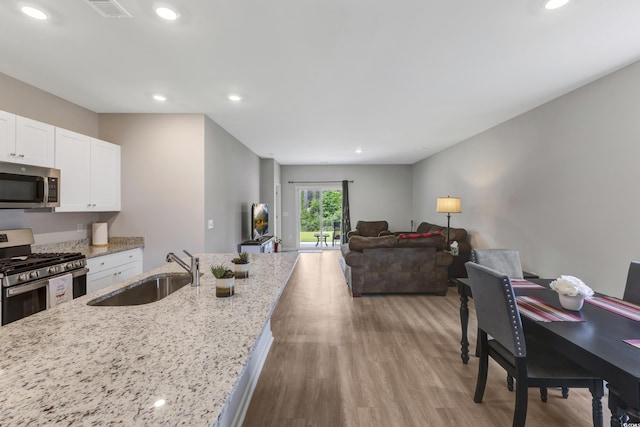 120 Carolina Lakes Blvd, Myrtle Beach, SC 29588 - kitchen with stainless steel appliances, a sink, white cabinets, wood finished floors, and light stone counters