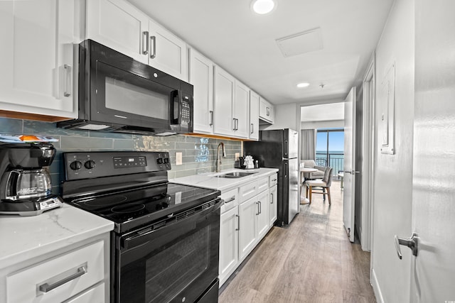 3000 N Ocean Blvd N Unit 531, Myrtle Beach, SC 29577 - kitchen featuring black appliances, a sink, white cabinets, light wood-style flooring, and tasteful backsplash