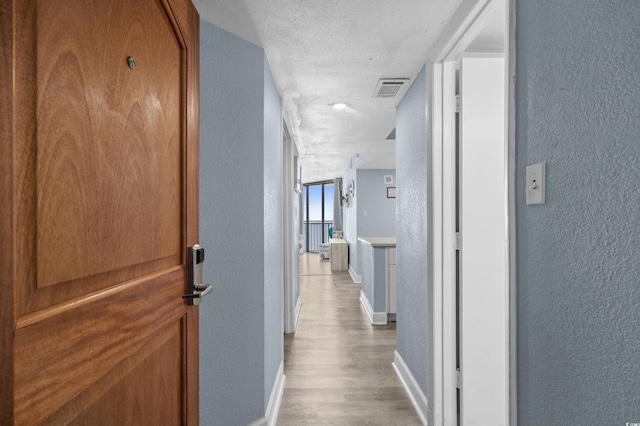 9550 Shore Dr Unit 529, Myrtle Beach, SC 29572 - hallway featuring a textured wall, baseboards, light wood-style flooring, and a textured ceiling