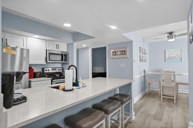 9550 Shore Dr Unit 529, Myrtle Beach, SC 29572 - kitchen with stainless steel appliances, a kitchen bar, white cabinets, a sink, and light wood-style floors