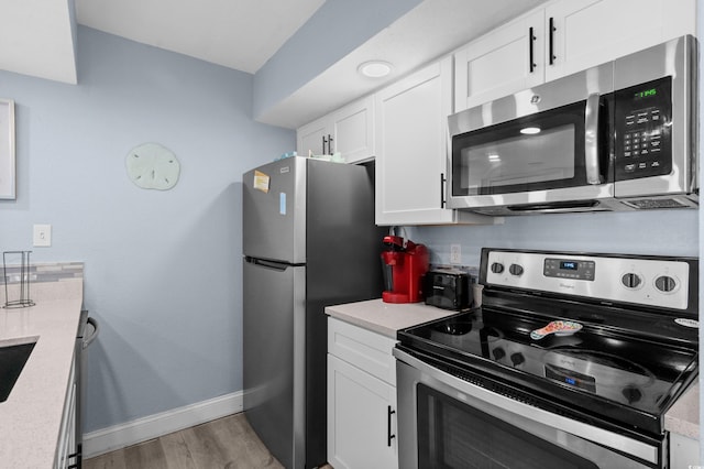 9550 Shore Dr Unit 529, Myrtle Beach, SC 29572 - kitchen with appliances with stainless steel finishes, baseboards, light countertops, light wood finished floors, and white cabinetry