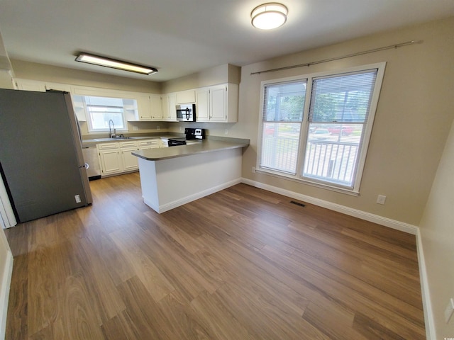 302 Silver Fox Trl, Myrtle Beach, SC 29588 - kitchen with stainless steel appliances, a sink, a peninsula, dark wood-type flooring, and white cabinetry