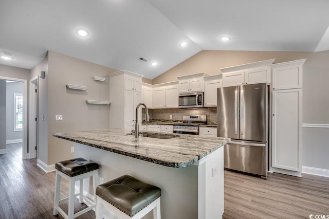 3129 Slade Dr, Conway, SC 29526 - kitchen with stainless steel appliances, a sink, light wood-type flooring, white cabinets, and lofted ceiling