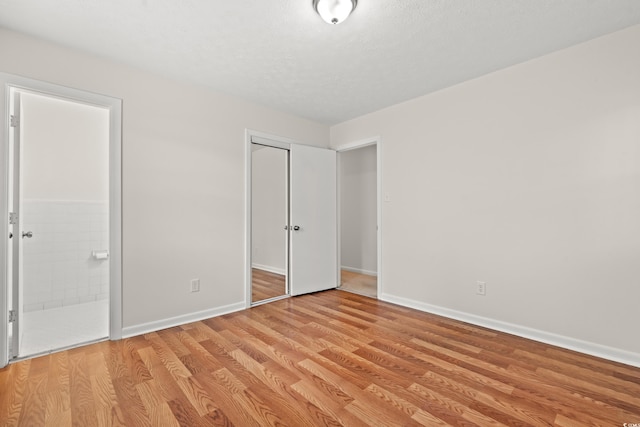 203 Longwood Ln, Conway, SC 29527 - unfurnished bedroom with light wood-style flooring, connected bathroom, a closet, baseboards, and a textured ceiling