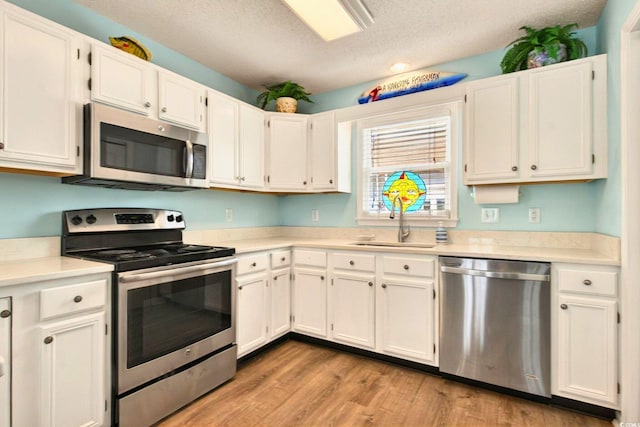 6 Indigo Ct, Ocean Isle Beach, NC 28469 - kitchen featuring stainless steel appliances, a textured ceiling, light countertops, light wood finished floors, and white cabinets