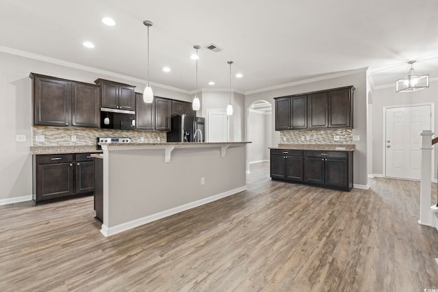 148 Long Leaf Pine Dr, Conway, SC 29526 - kitchen with refrigerator with ice dispenser, stainless steel microwave, arched walkways, dark brown cabinets, and decorative backsplash