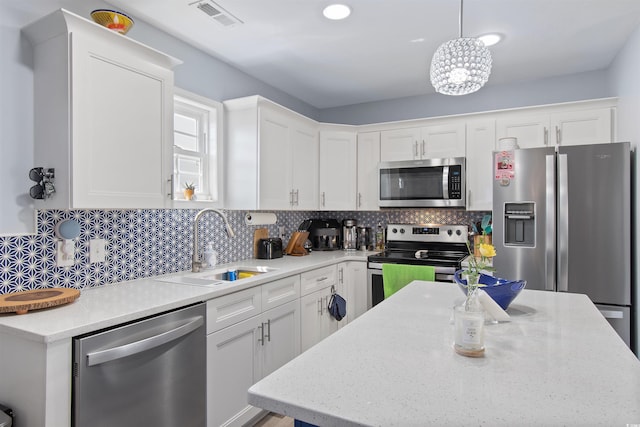 104 Clovis Cir, Myrtle Beach, SC 29579 - kitchen featuring stainless steel appliances, a sink, white cabinets, decorative backsplash, and hanging light fixtures