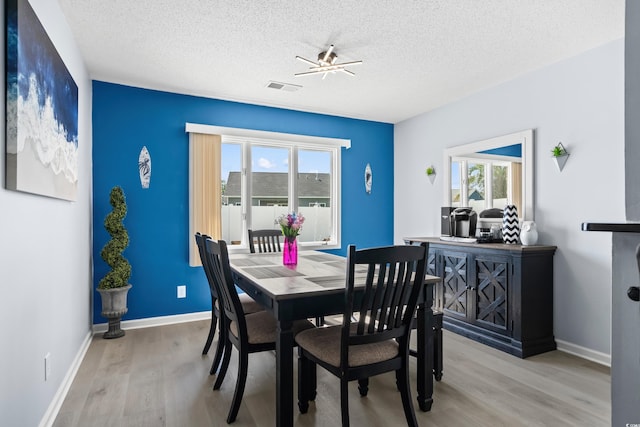 502 Garden Dr, Surfside Beach, SC 29575 - dining room with light wood-style floors, a textured ceiling, and baseboards