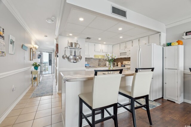 1210 N Waccamaw Dr Unit 1105, Murrells Inlet, SC 29576 - kitchen with white appliances, crown molding, recessed lighting, white cabinetry, and decorative backsplash