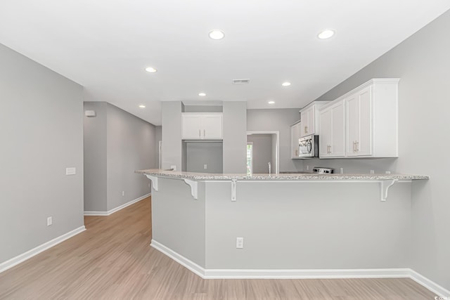 3539 Harrelson Ave, Loris, SC 29569 - kitchen with stainless steel microwave, a kitchen bar, baseboards, a peninsula, and recessed lighting