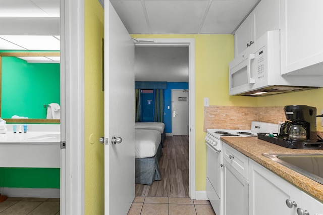 2207 S Ocean Blvd Unit 1517, Myrtle Beach, SC 29577 - kitchen featuring white appliances, white cabinets, light tile patterned floors, light countertops, and baseboards