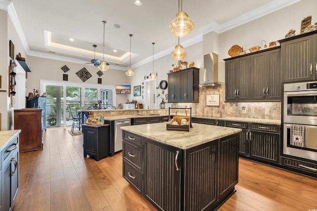 81 Cascade Dr, Murrells Inlet, SC 29576 - kitchen featuring appliances with stainless steel finishes, wall chimney range hood, a center island, a raised ceiling, and wood-type flooring