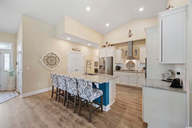 2300 Lark Sparrow St, Myrtle Beach, SC 29577 - kitchen featuring appliances with stainless steel finishes, wall chimney range hood, a sink, white cabinetry, and a kitchen breakfast bar