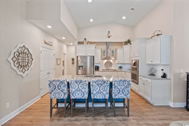 2300 Lark Sparrow St, Myrtle Beach, SC 29577 - kitchen with stainless steel appliances, wall chimney range hood, white cabinets, a breakfast bar area, and a kitchen island with sink