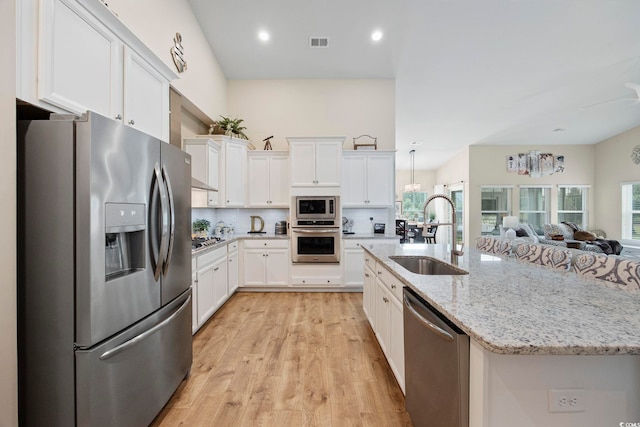 2300 Lark Sparrow St, Myrtle Beach, SC 29577 - kitchen featuring appliances with stainless steel finishes, a sink, open floor plan, white cabinets, and decorative backsplash