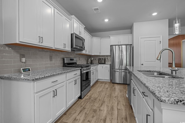 1168 Baker Creek Loop, Myrtle Beach, SC 29579 - kitchen featuring stainless steel appliances, a sink, white cabinets, light wood-style flooring, and hanging light fixtures