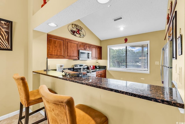 201 Westleton Dr Unit 10-I, Myrtle Beach, SC 29572 - kitchen featuring appliances with stainless steel finishes, lofted ceiling, a kitchen breakfast bar, dark stone counters, and a peninsula