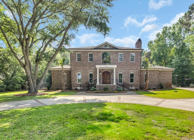 2382 Waverly Rd, Pawleys Island, SC 29585 - colonial-style house featuring brick siding, a chimney, a front yard, and curved driveway