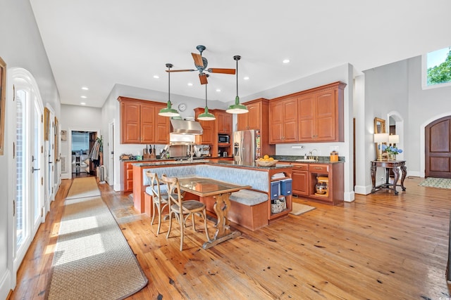 2382 Waverly Rd, Pawleys Island, SC 29585 - kitchen with stainless steel fridge, arched walkways, a ceiling fan, an island with sink, and light wood-type flooring