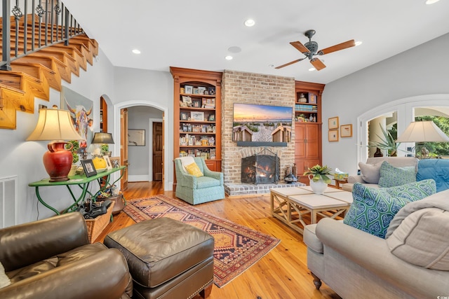 2382 Waverly Rd, Pawleys Island, SC 29585 - living room with arched walkways, a ceiling fan, hardwood / wood-style flooring, a fireplace, and built in shelves