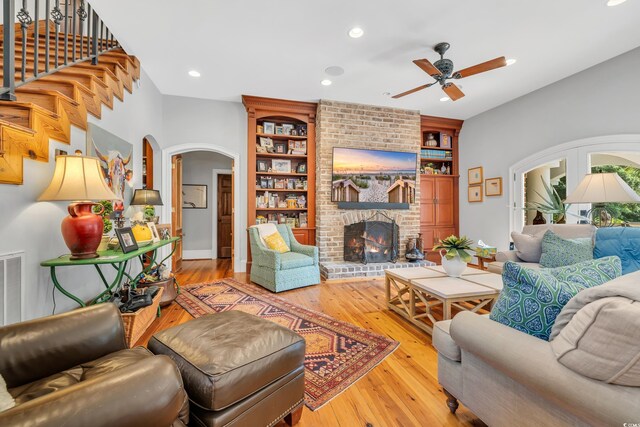 2382 Waverly Rd, Pawleys Island, SC 29585 - living room with arched walkways, a ceiling fan, hardwood / wood-style flooring, a fireplace, and built in shelves