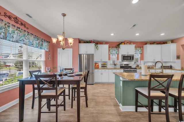 1145 Captain Hooks Way N, Myrtle Beach, SC 29582 - kitchen with appliances with stainless steel finishes, light wood-style floors, a chandelier, white cabinetry, and a breakfast bar