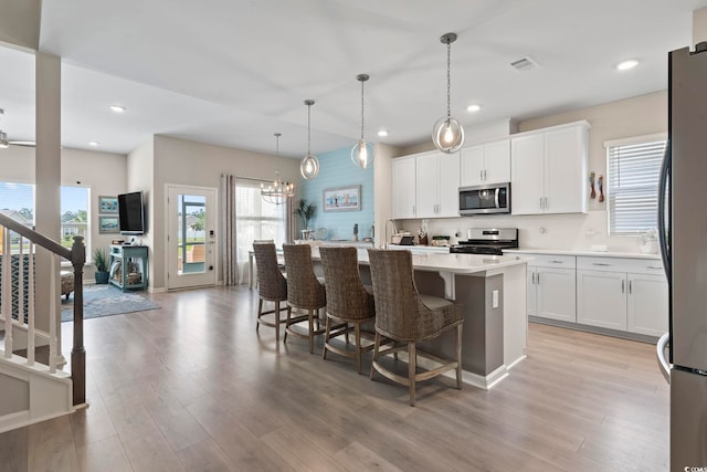 2572 Brescia St, Myrtle Beach, SC 29579 - kitchen with stainless steel appliances, light countertops, a center island with sink, white cabinets, and light wood-type flooring