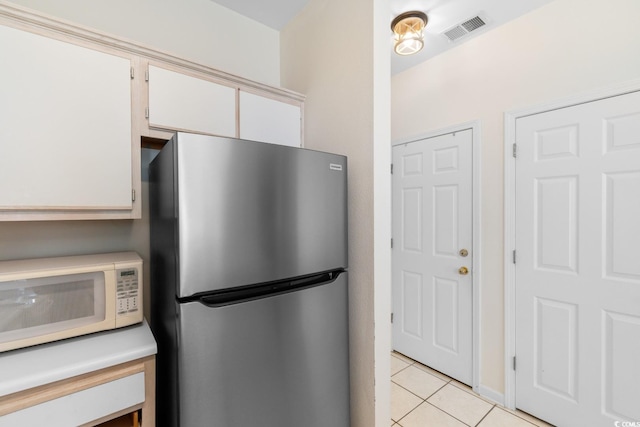 1298 River Oaks Dr Unit 5-I, Myrtle Beach, SC 29579 - kitchen featuring freestanding refrigerator, white microwave, light tile patterned floors, white cabinetry, and light countertops