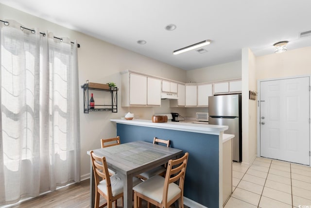 1298 River Oaks Dr Unit 5-I, Myrtle Beach, SC 29579 - kitchen with freestanding refrigerator, under cabinet range hood, light countertops, a peninsula, and white microwave
