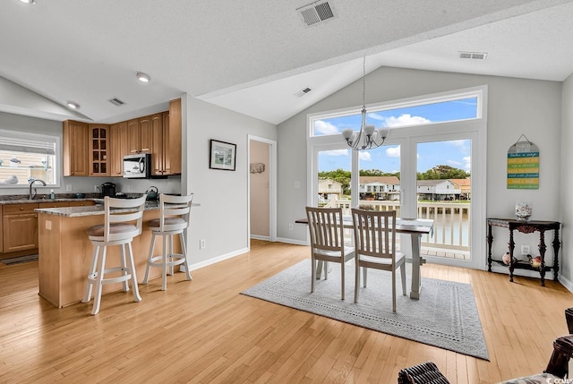 521 Bay Dr, Garden City Beach, SC 29576 - dining area with vaulted ceiling, light wood-type flooring, a chandelier, baseboards, and a textured ceiling