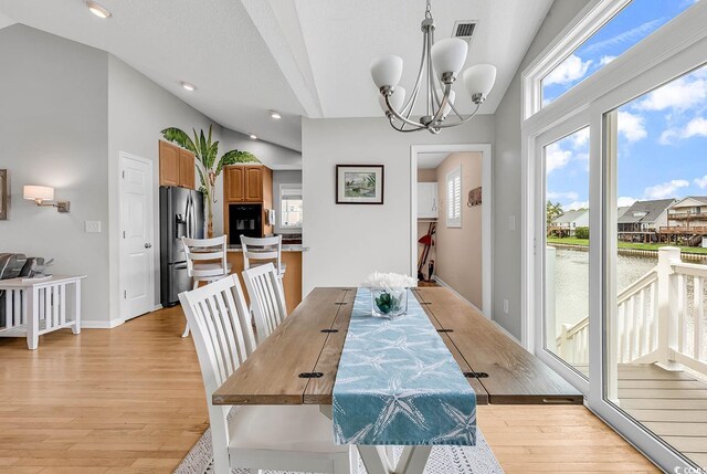 521 Bay Dr, Garden City Beach, SC 29576 - dining room with lofted ceiling, light wood finished floors, a chandelier, a water view, and recessed lighting