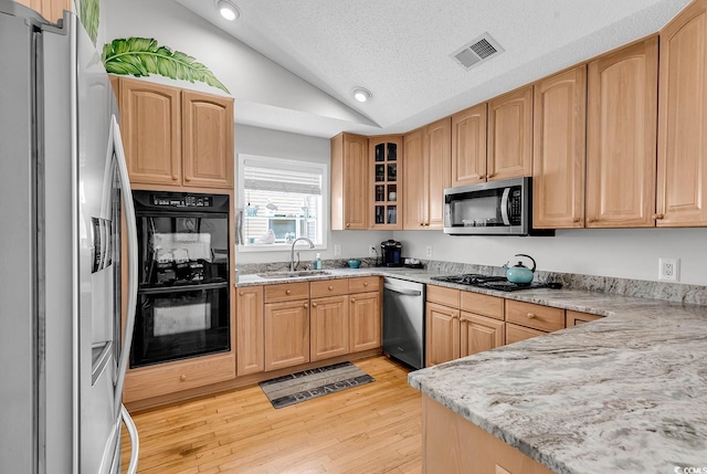 521 Bay Dr, Garden City Beach, SC 29576 - kitchen featuring black appliances, vaulted ceiling, a sink, light wood-type flooring, and light stone countertops