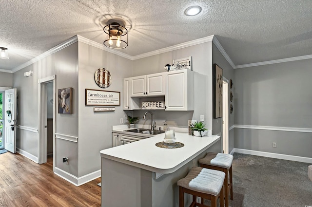 4251 Hibiscus Dr Unit 202, Little River, SC 29566 - kitchen with a sink, a textured ceiling, a breakfast bar area, white cabinetry, and light countertops