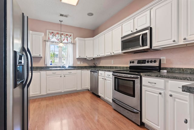 618 5th Ave S, North Myrtle Beach, SC 29582 - kitchen with appliances with stainless steel finishes, white cabinets, dark countertops, and a sink