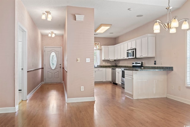 618 5th Ave S, North Myrtle Beach, SC 29582 - kitchen featuring stainless steel appliances, dark countertops, white cabinetry, light wood-style flooring, and baseboards