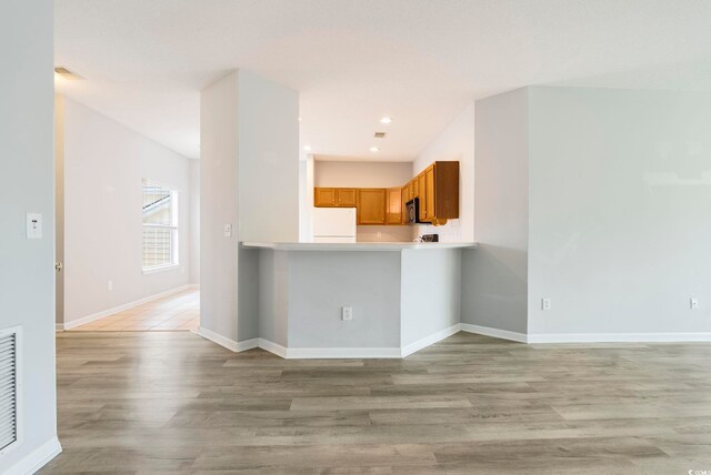 4430-G Montrose Ln Unit G, Myrtle Beach, SC 29579 - kitchen with freestanding refrigerator, brown cabinetry, light wood-type flooring, stainless steel microwave, and light countertops