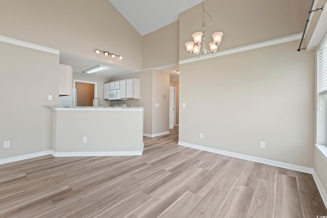 4924 Pond Shoals Ct Unit 201, Myrtle Beach, SC 29579 - unfurnished living room with a chandelier, high vaulted ceiling, light wood-type flooring, baseboards, and a sink