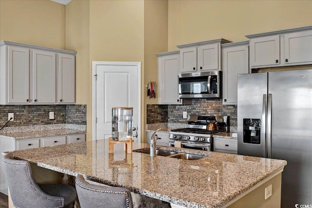 1631 Hepburn Dr, Little River, SC 29566 - kitchen featuring stainless steel appliances, a sink, decorative backsplash, light stone counters, and a high ceiling