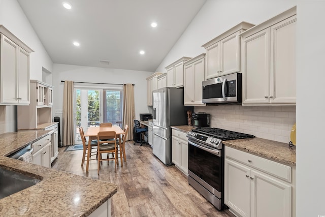 450 Oaklanding Ln, Murrells Inlet, SC 29576 - kitchen with appliances with stainless steel finishes, tasteful backsplash, lofted ceiling, light stone counters, and light wood finished floors
