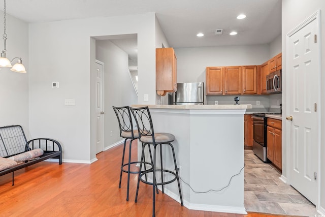 314 Kiskadee Loop Unit 8-C, Conway, SC 29526 - kitchen featuring stainless steel appliances, a breakfast bar area, brown cabinets, recessed lighting, and light countertops