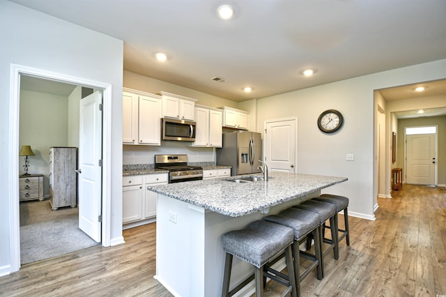 2315 Blackthorn Dr, Conway, SC 29526 - kitchen with appliances with stainless steel finishes, an island with sink, a kitchen breakfast bar, white cabinets, and light wood finished floors