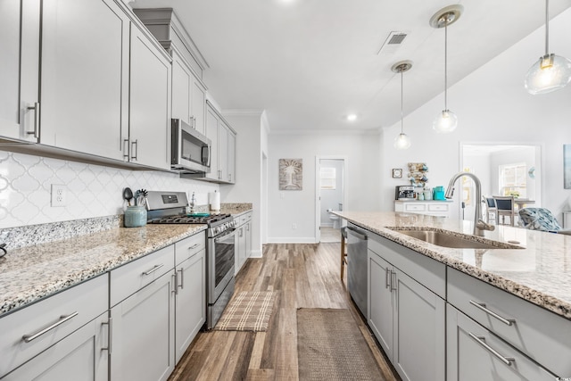 1008 Mary Read Dr, North Myrtle Beach, SC 29582 - kitchen featuring appliances with stainless steel finishes, a sink, wood finished floors, gray cabinetry, and tasteful backsplash