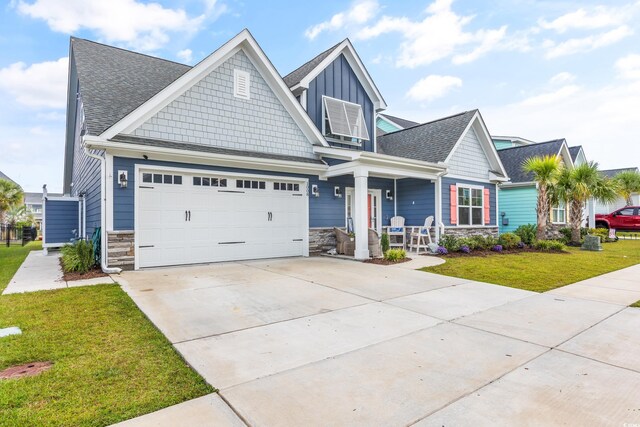 1008 Mary Read Dr, North Myrtle Beach, SC 29582 - craftsman-style house featuring a porch, a front yard, concrete driveway, stone siding, and board and batten siding