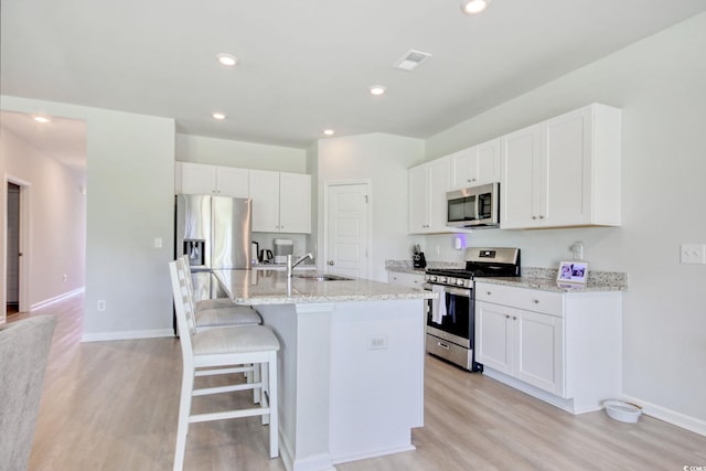212 Carolina Lakes Blvd, Myrtle Beach, SC 29588 - kitchen featuring appliances with stainless steel finishes, a sink, light wood-style floors, a breakfast bar area, and an island with sink