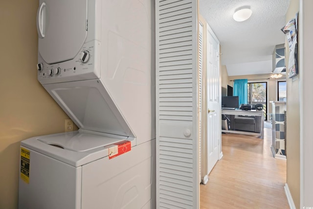 1100 Possum Trot Rd Unit C-203, North Myrtle Beach, SC 29582 - washroom featuring estacked washer and dryer, light wood-style floors, and a textured ceiling